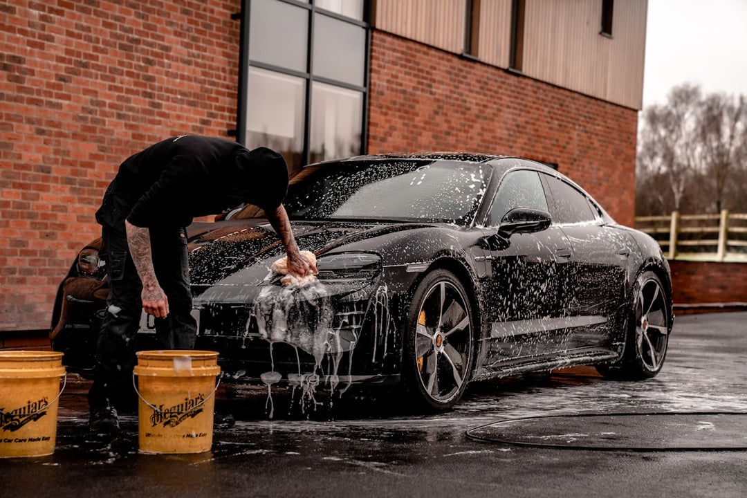 Person cleaning matte black aftermarket wheels with a microfiber cloth